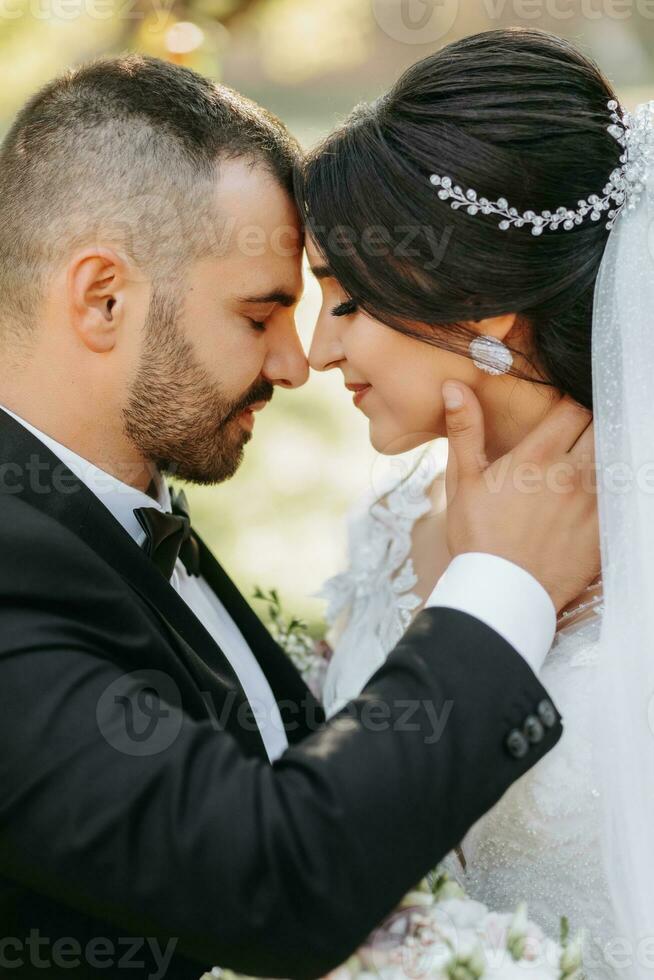 Portrait of a happy newlywed wife and husband hugging outdoors and enjoying a wedding bouquet of white roses. Sincere feelings of two young people. The concept of true love. photo