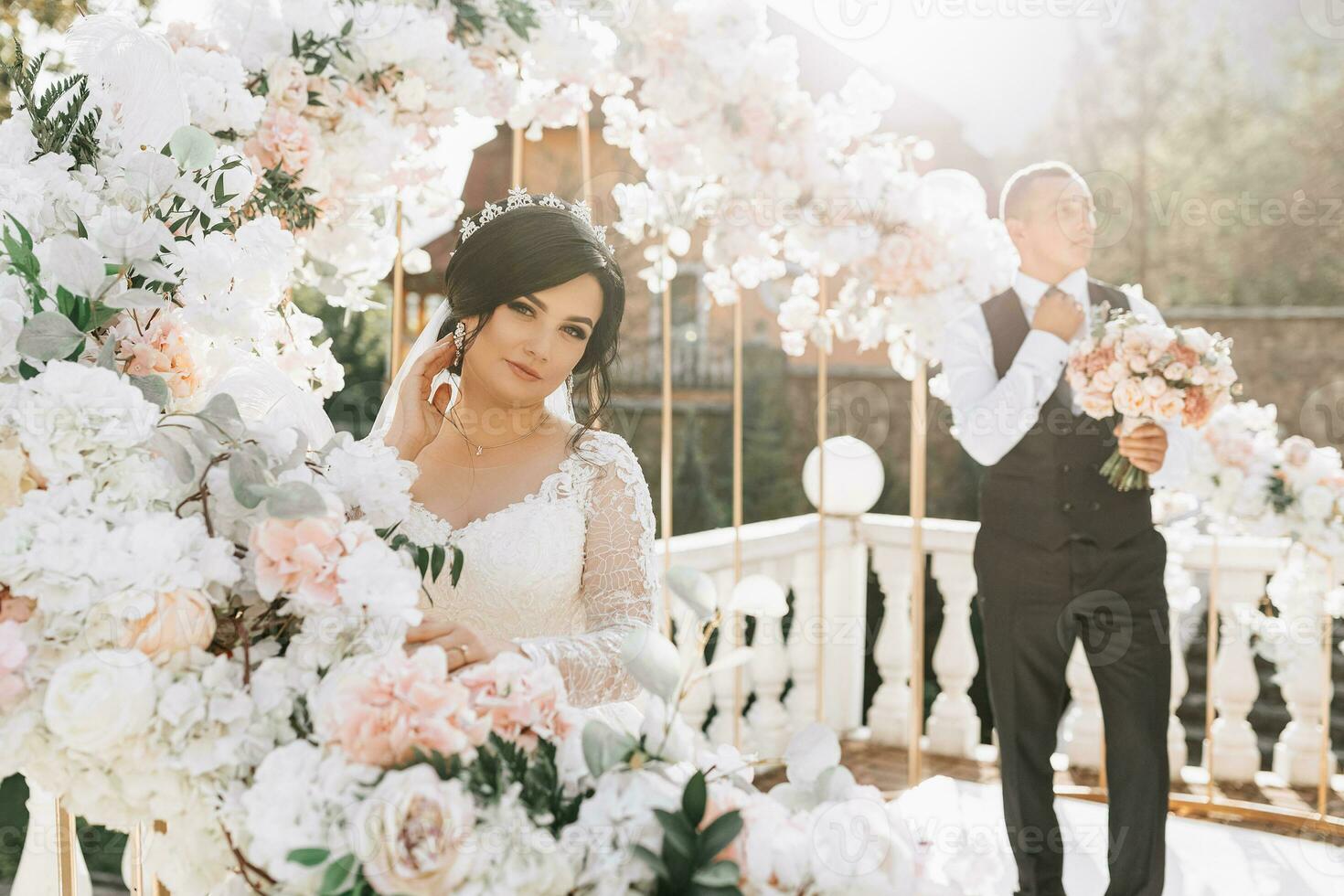 contento novia y novio son posando a el Boda ceremonia. el Boda arco es decorado con Rosa flores foto