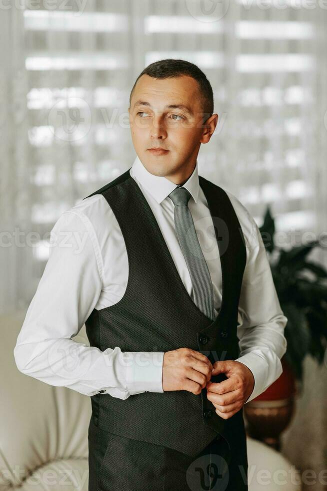 un empresario es consiguiendo vestido en preparación para un reunión. el novio es preparando para el boda. el hombre es vistiendo un blanco camisa. elegante novio foto