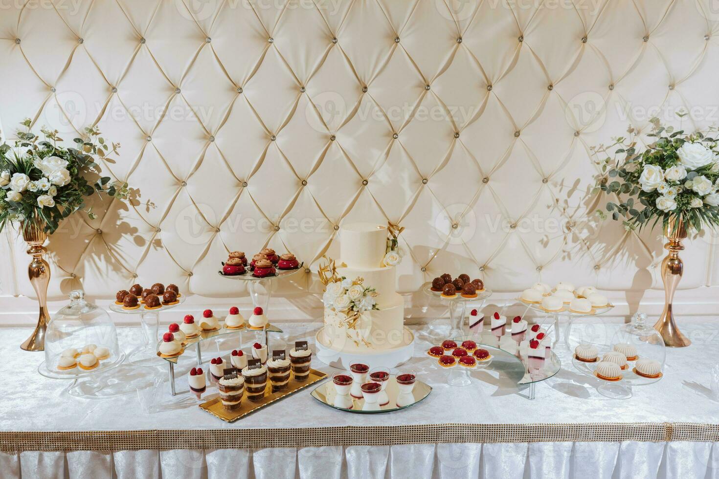 un delicioso boda. beige pastel decorado con flores caramelo bar con varios chocolate dulces celebracion concepto. de moda postres mesa con dulces, dulces. foto