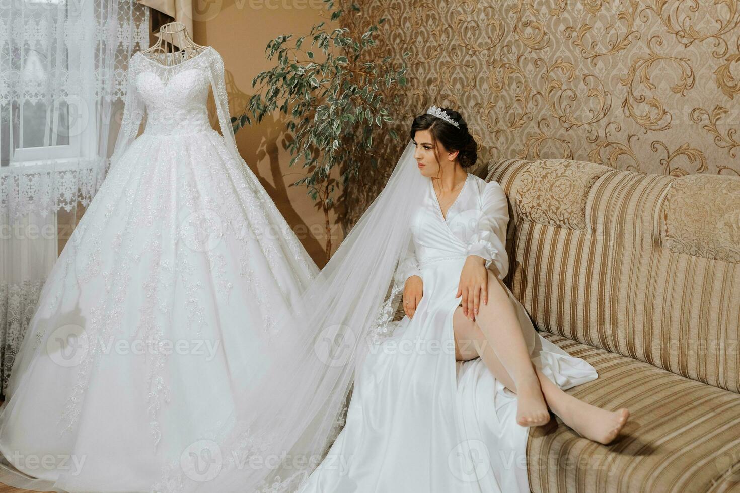 Romantic atmosphere of the bride's morning. Bride in a home. Bride morning preparation. Bride in beautiful dress near the mannequin with dress indoors at home. Enjoy every moment photo