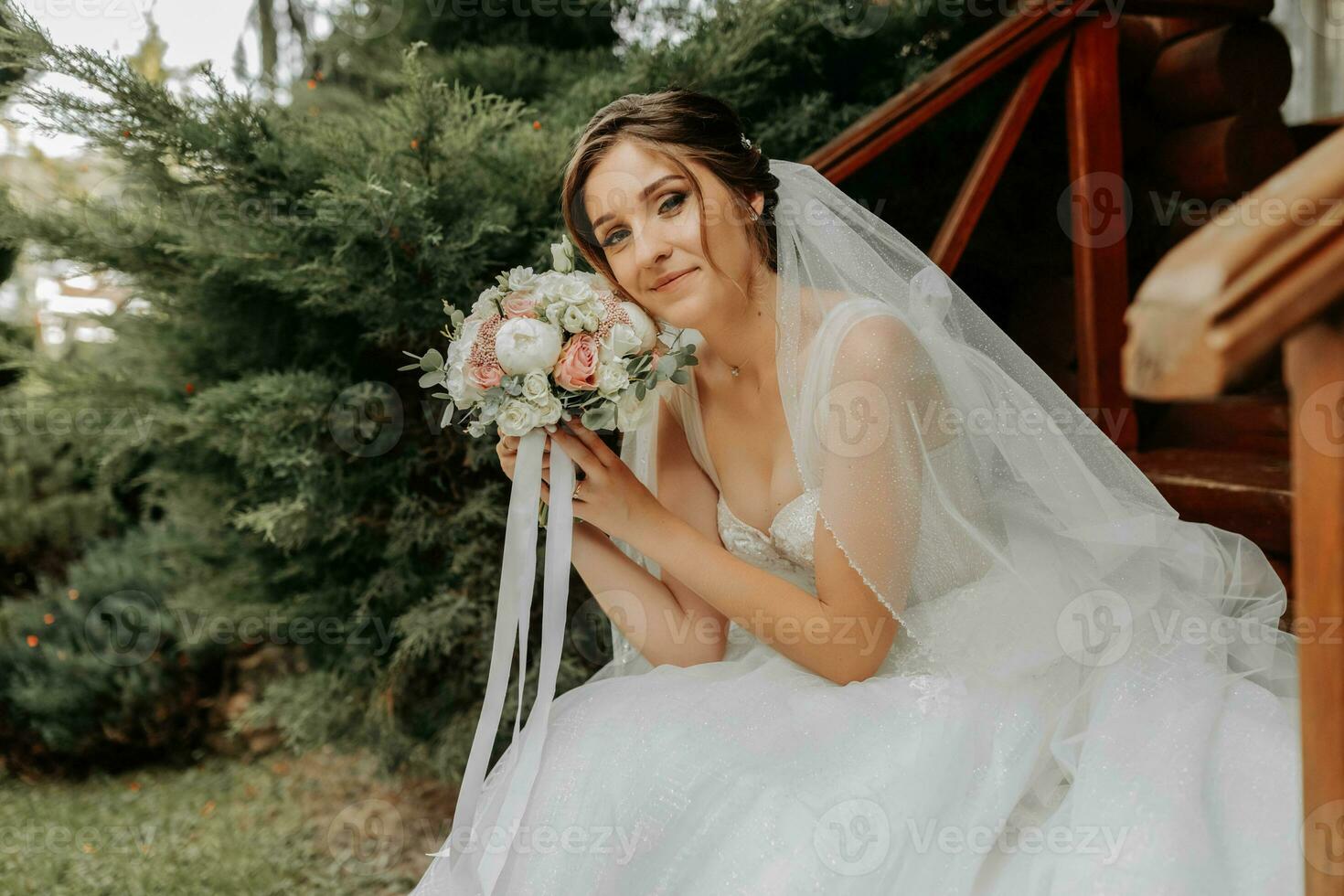 Beautiful bride in a fashionable wedding dress on a natural background in the park. A stunning young bride is incredibly happy. Happy girl on her wedding day photo