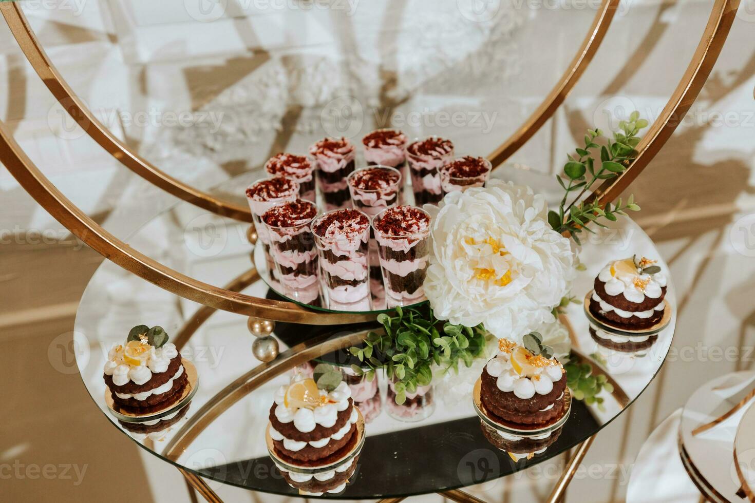 A delicious wedding. Beige cake decorated with flowers. Candy bar with various chocolate sweets. Celebration concept. Fashionable desserts. Table with sweets, candies. photo