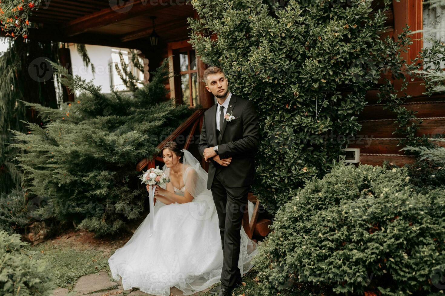 maravilloso elegante lujoso novia con velo soplo en el viento. y un elegante novio Beso al aire libre cerca alto otoño arboles foto