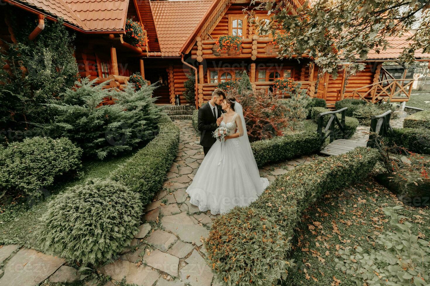 gorgeous elegant luxurious bride with veil blowing in the wind. and a stylish groom kiss outdoors near tall autumn trees photo