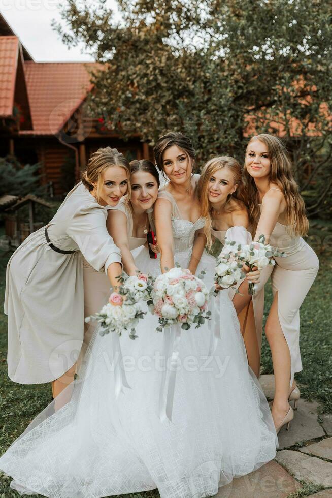 grupo de hermosa mujer en idéntico vestidos sonriente, celebrando y teniendo divertido juntos. amigos de el novia celebrar el Boda juntos con el novia en naturaleza foto