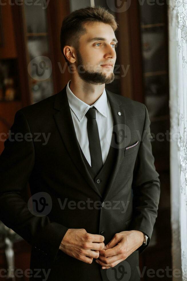 el hombre sujeta el botones en su chaqueta. el novio es preparando para el Boda ceremonia. detallado de cerca foto de manos