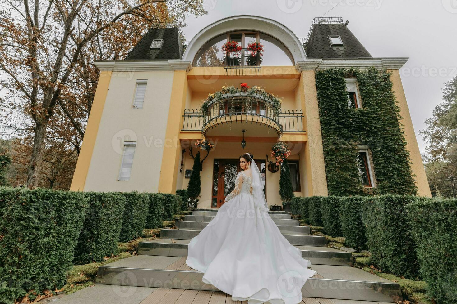 Gorgeous bride in wedding dress with long train and veil outdoors. The bride against the background of an expensive hotel photo