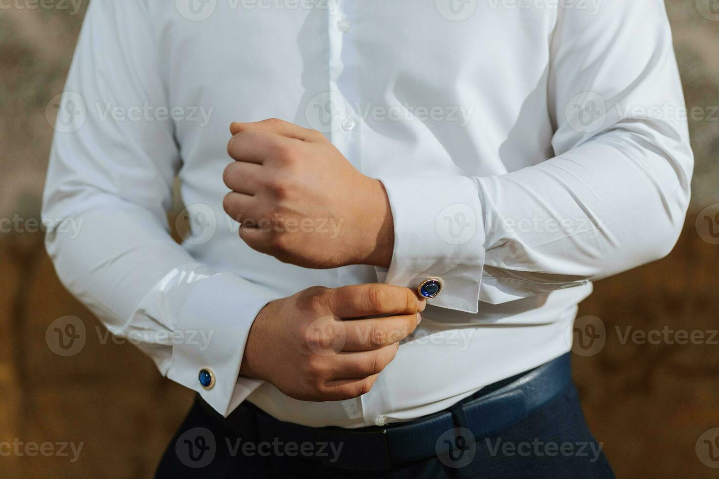 Close-up portrait of a man at home, buttoning his shirt. The groom is preparing for the wedding. The man is wearing a white shirt. Stylish groom photo