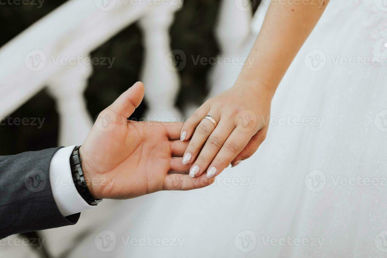 Close-up of groom's hand holding bride's wirst tender photo