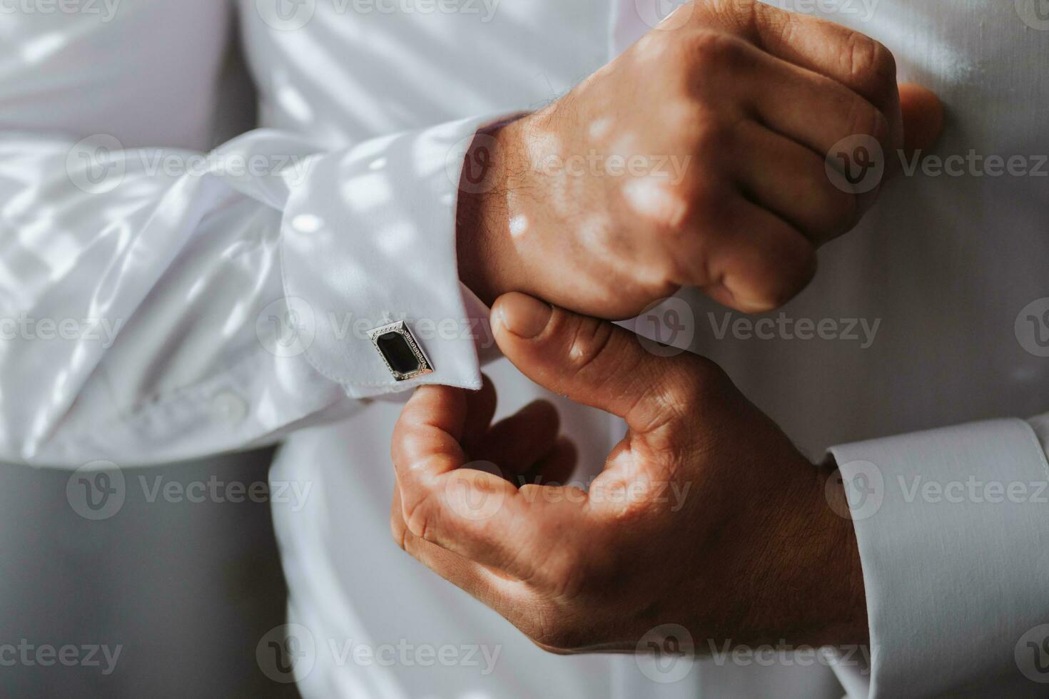 Handsome man putting on shirt standing near window at his room in morning. Preparing for some event or new workday. New opportunities, dating, wedding day or getting ready for job interview concept. photo