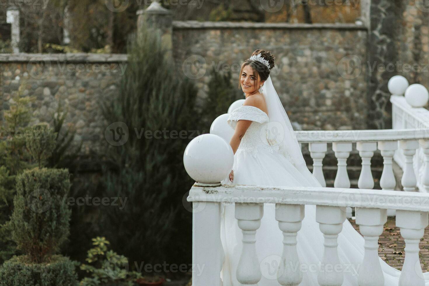 retrato de el novia en el balcón con un blanco barandilla. el novia en un Boda vestir en un natural antecedentes. Boda día. foto