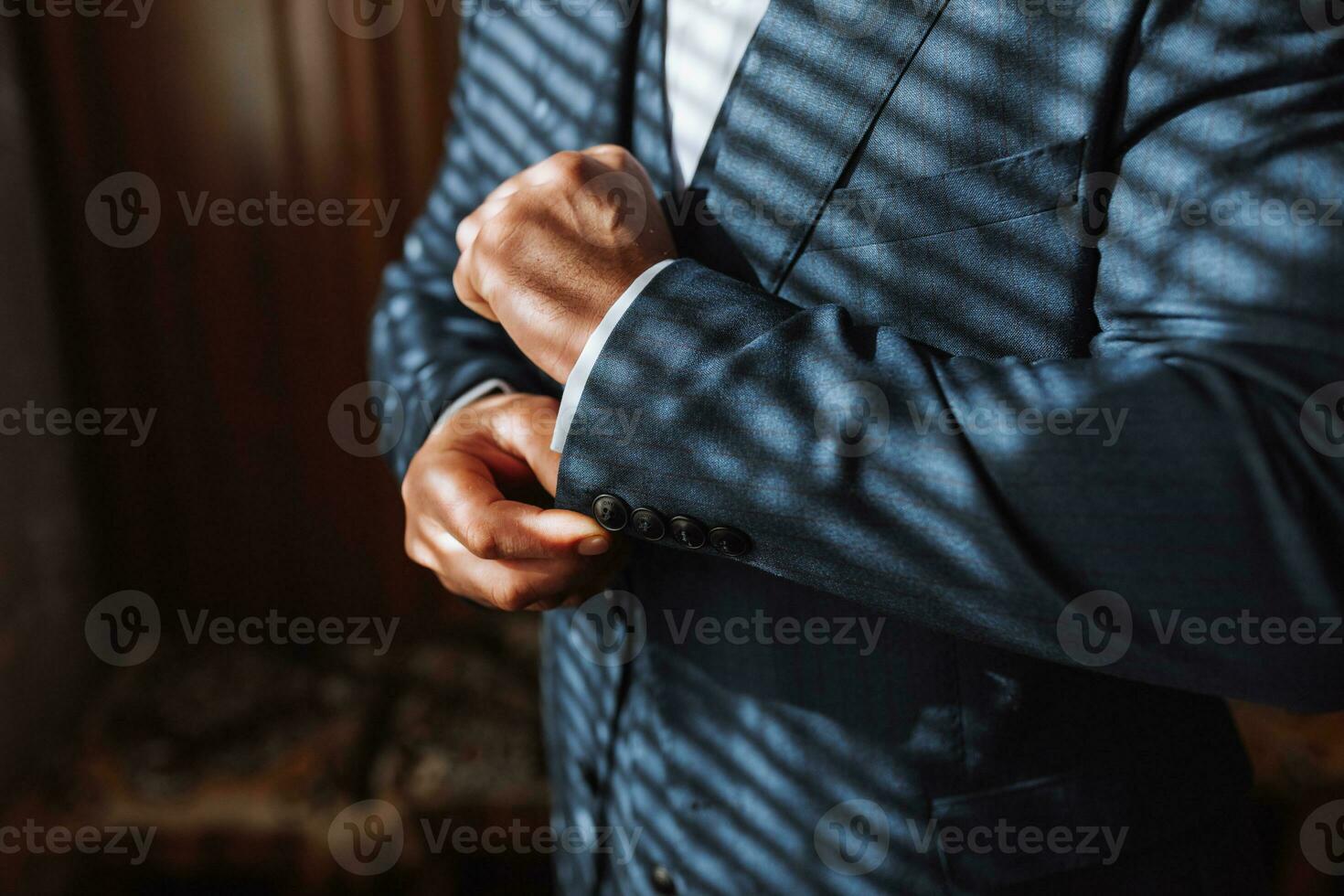 Male portrait. Photo session by the window. Groom's collection. The groom puts on a jacket. Wedding photo