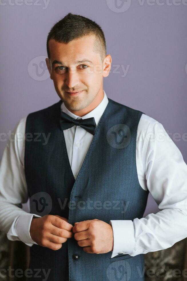 The groom puts on his vest in his room and prepares for the wedding. The man is preparing for the working day. photo