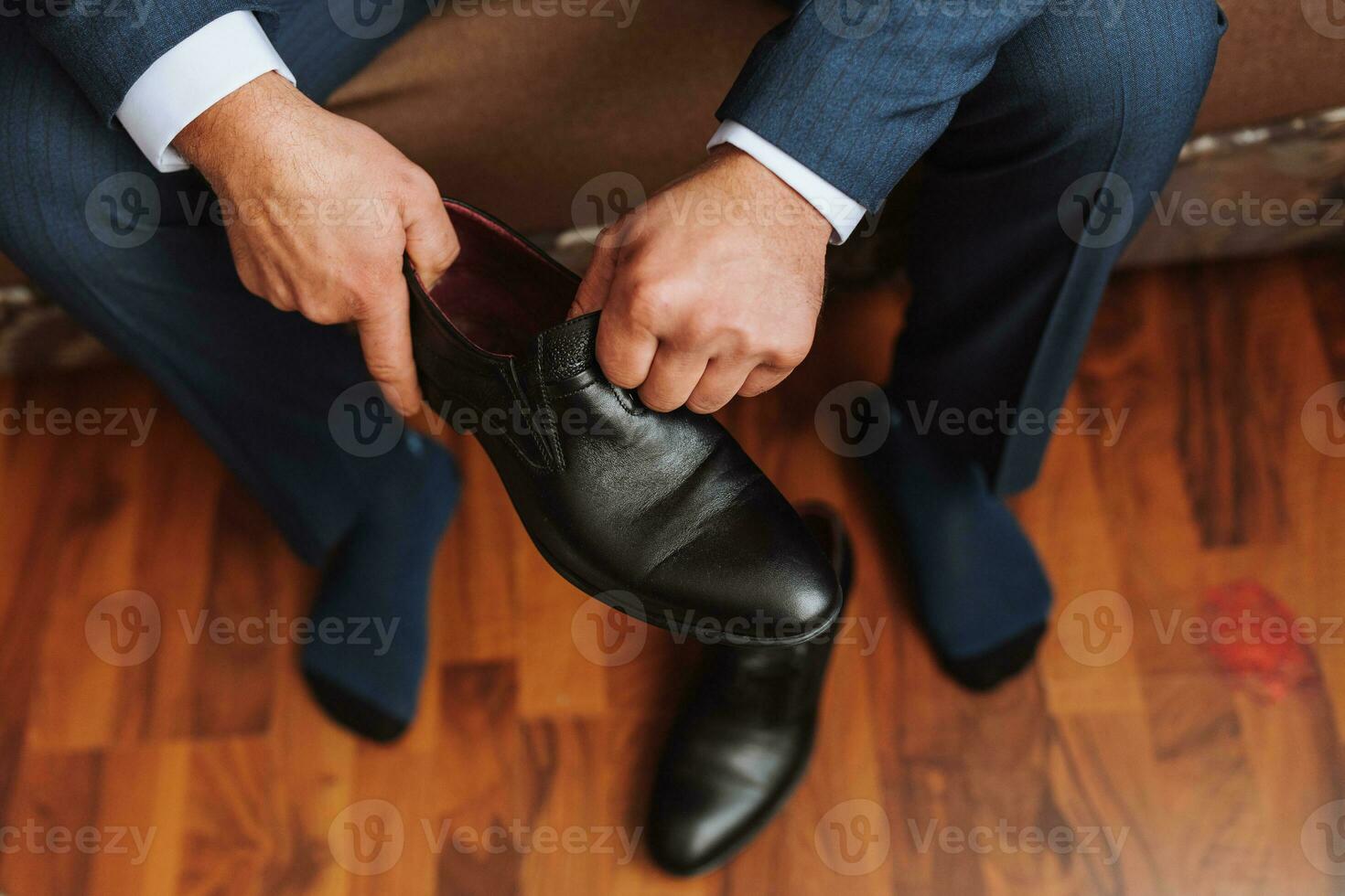 a man in a white shirt, lacing black shoes and preparing to meet his bride. The man wears classic black shoes photo