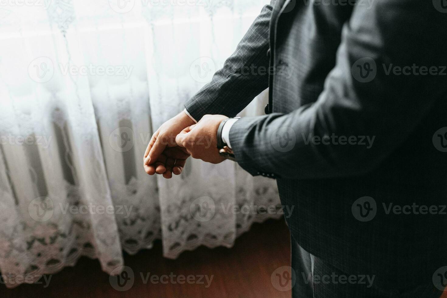 Male portrait. Photo session by the window. Groom's collection. The groom puts on a jacket. Wedding photo