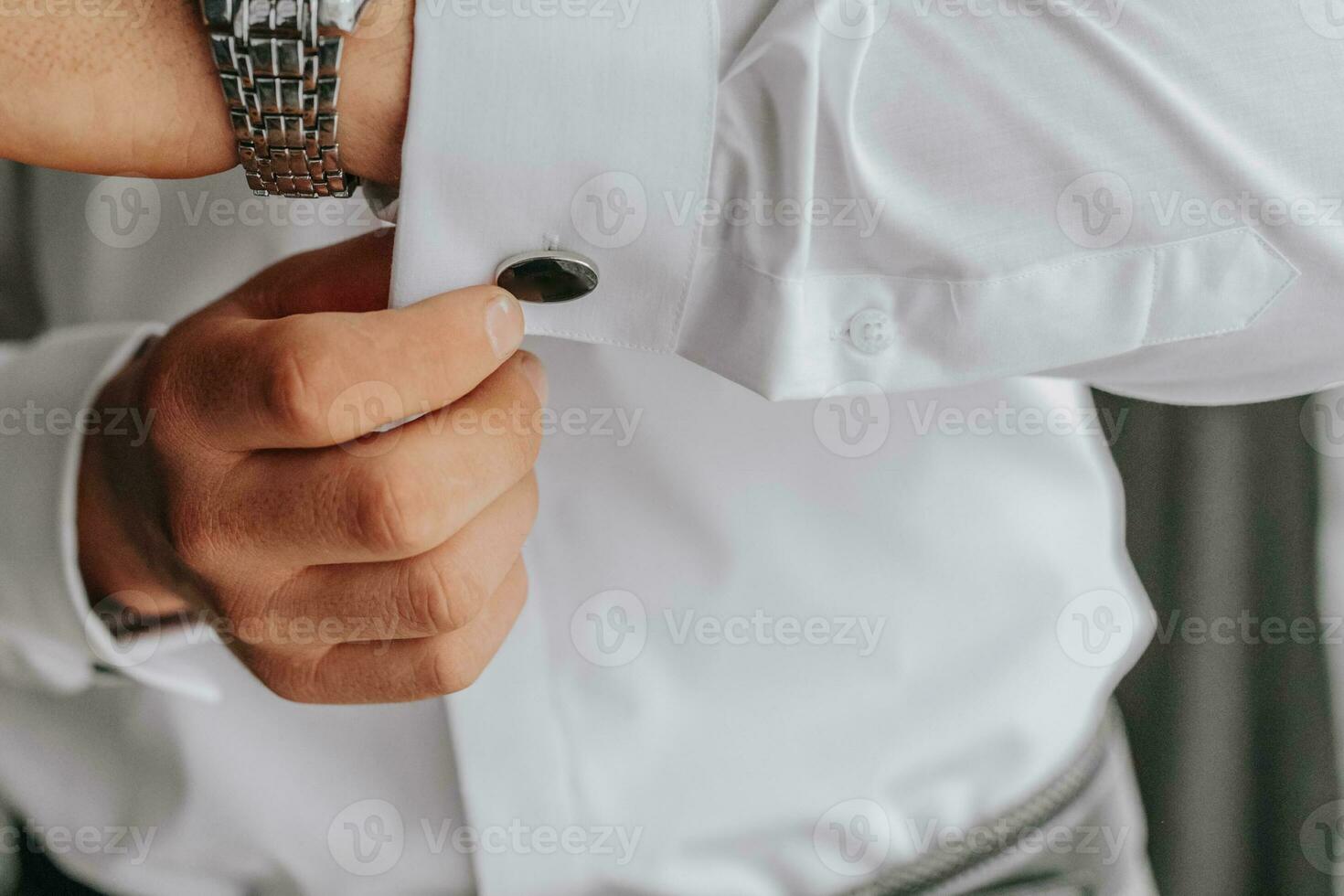 Close-up of man in white shirt adjusting cufflinks. the groom puts cufflinks photo