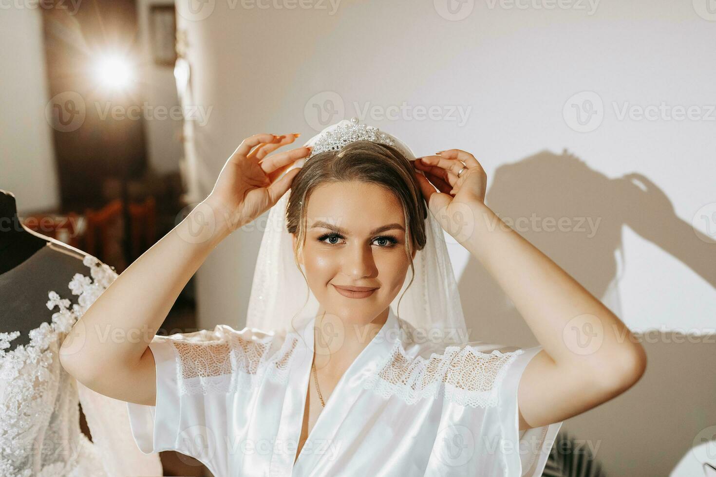 Romantic atmosphere of the morning of the bride in pajamas. Bride in the room. Preparation for the morning of the bride. Bride in beautiful dress near mannequin with dress indoors at home. photo