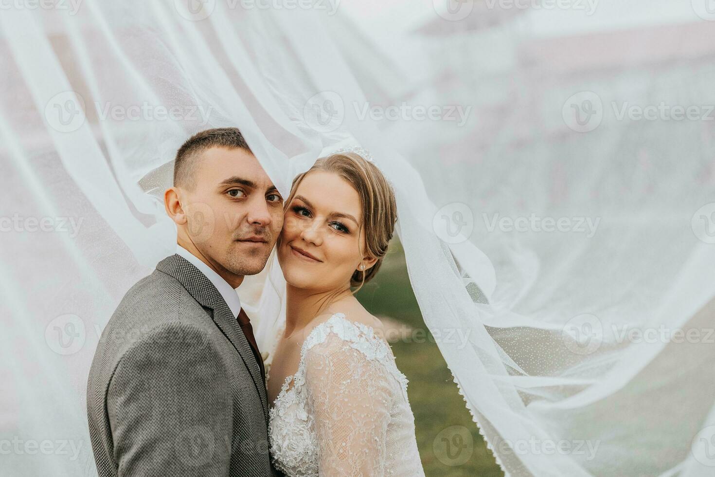 wedding couple on nature. bride and groom hugging under the veil at wedding. photo