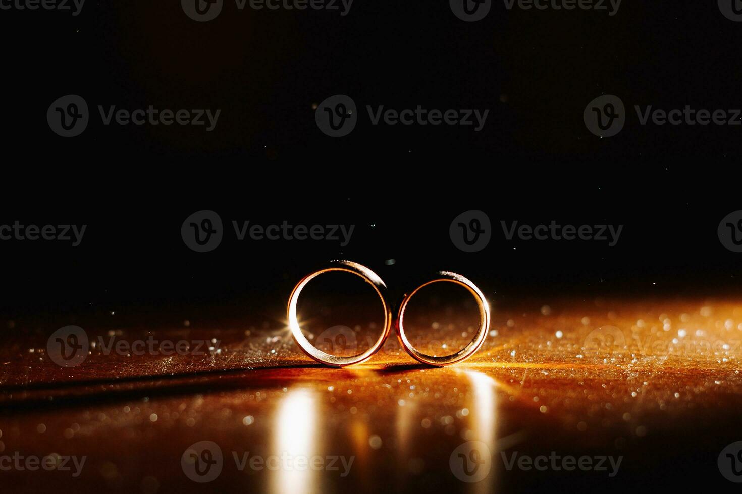 Two wedding rings in infinity sign with sparkling light mist. Love concept on black background photo