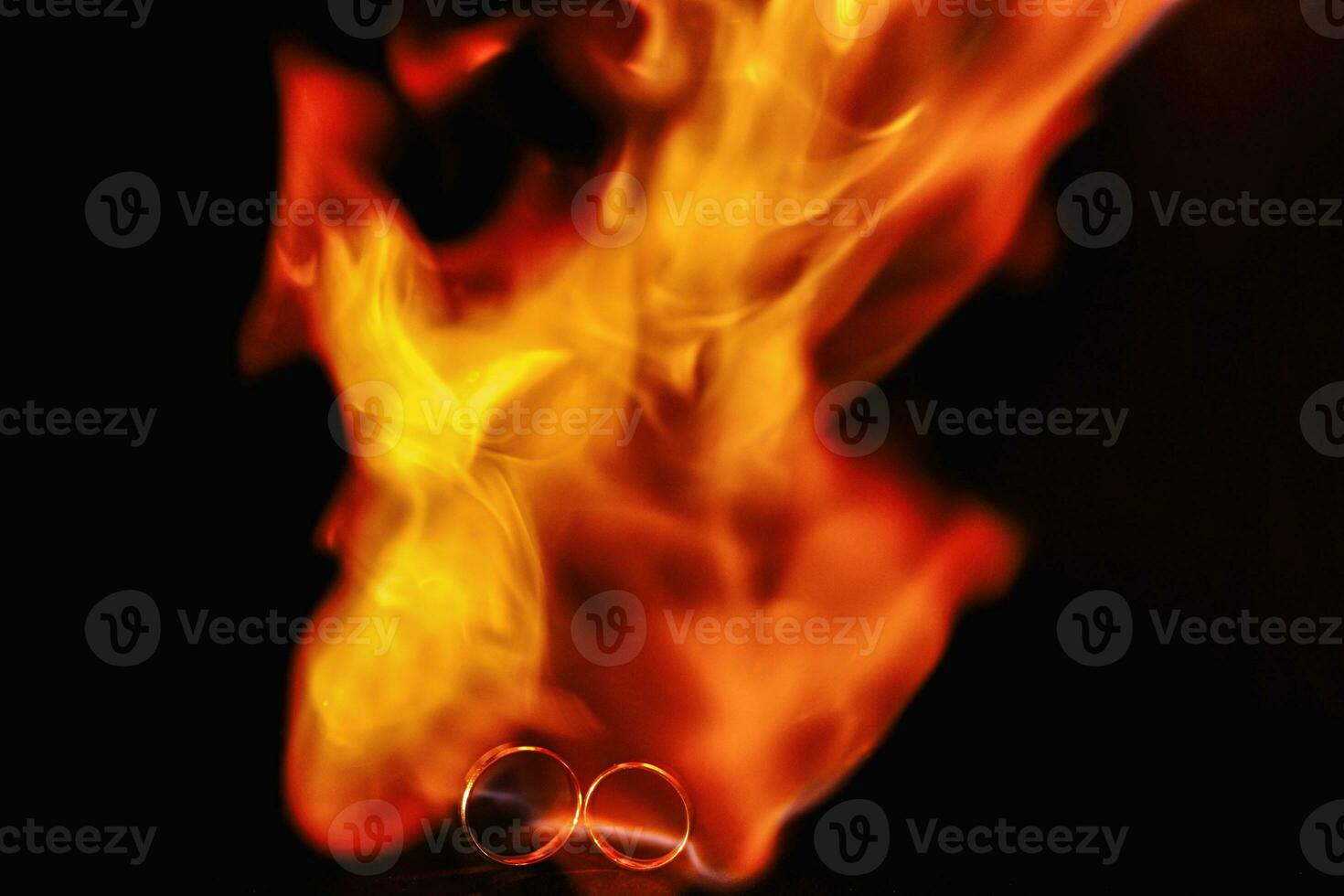 two wedding rings in the flames of fire. Wedding. Traditions. Fiery flame on a dark background photo