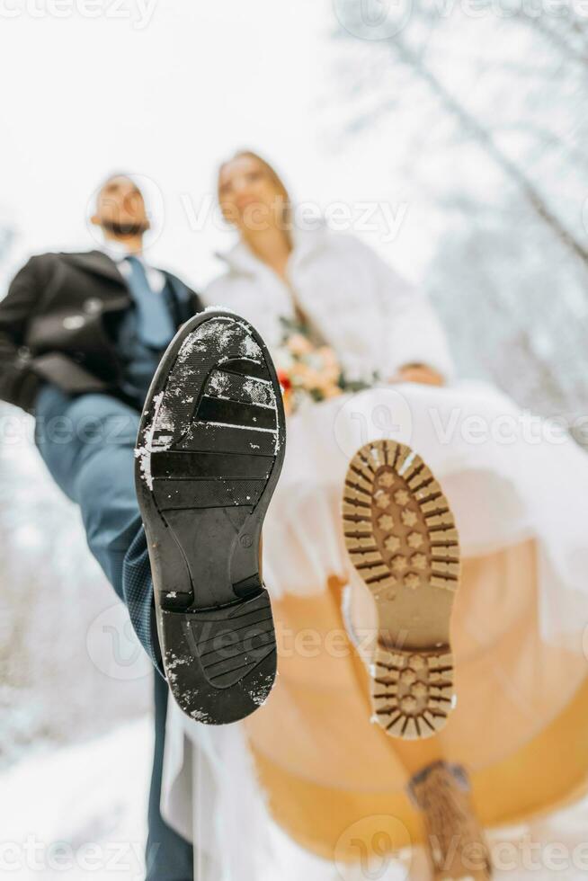 Groom and bride in leather boots at a winter wedding. Close-up of bride and groom shoes. Wedding in winter. photo