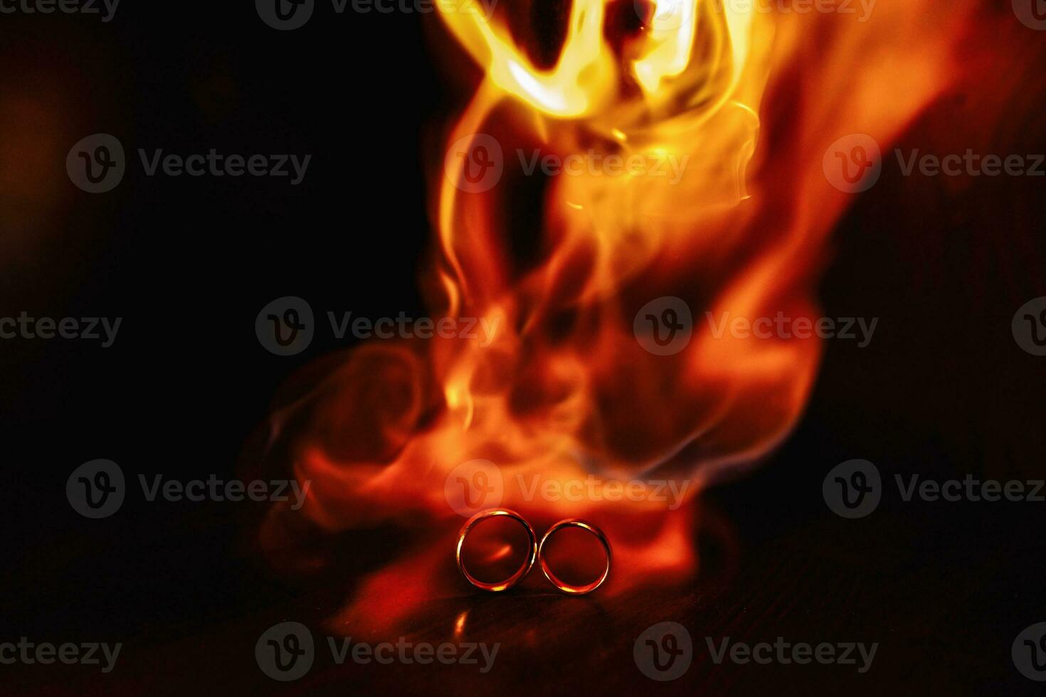 two wedding rings in the flames of fire. Wedding. Traditions. Fiery flame on a dark background photo