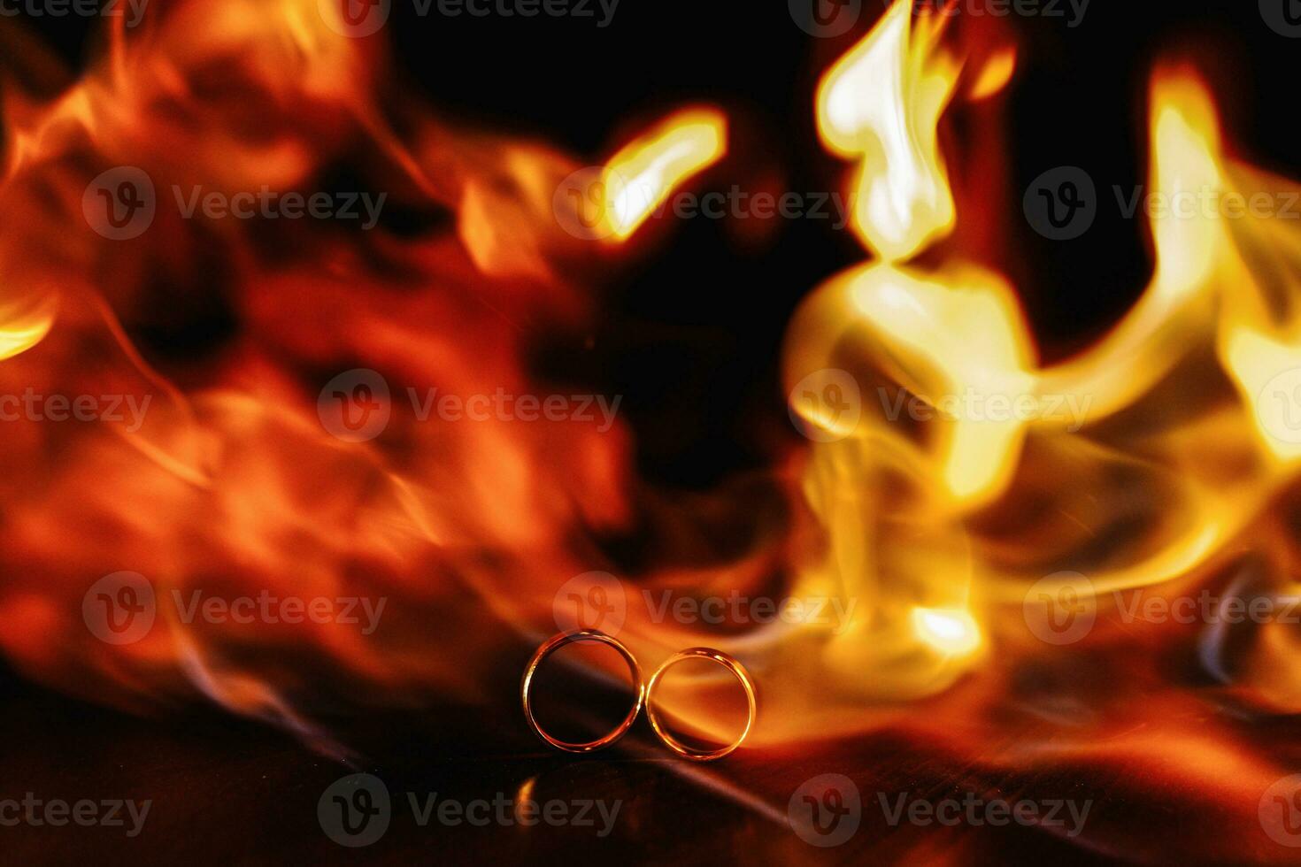 two wedding rings in a flame of fire on a dark background. Wedding. Traditions. Fire element photo