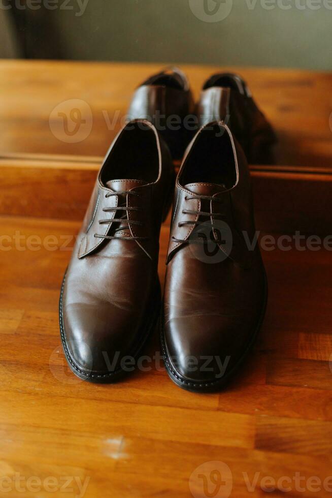brown men's leather shoes on the wooden floor near the mirror photo