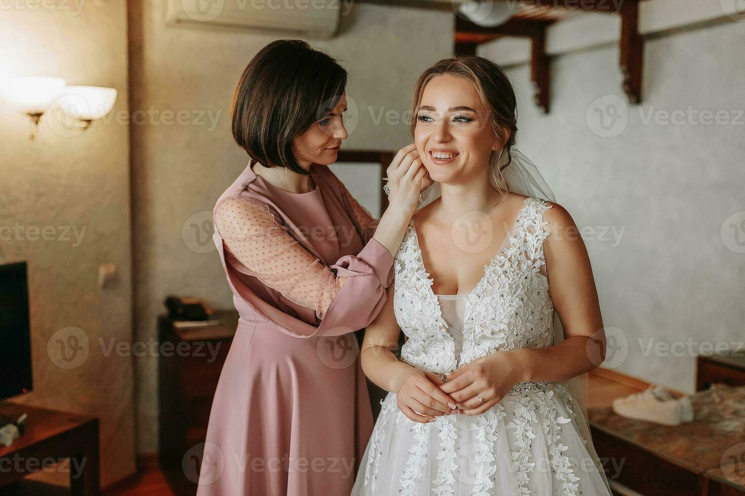 a friend is touching the bride's earring in the room. Preparation of the bride for the wedding photo