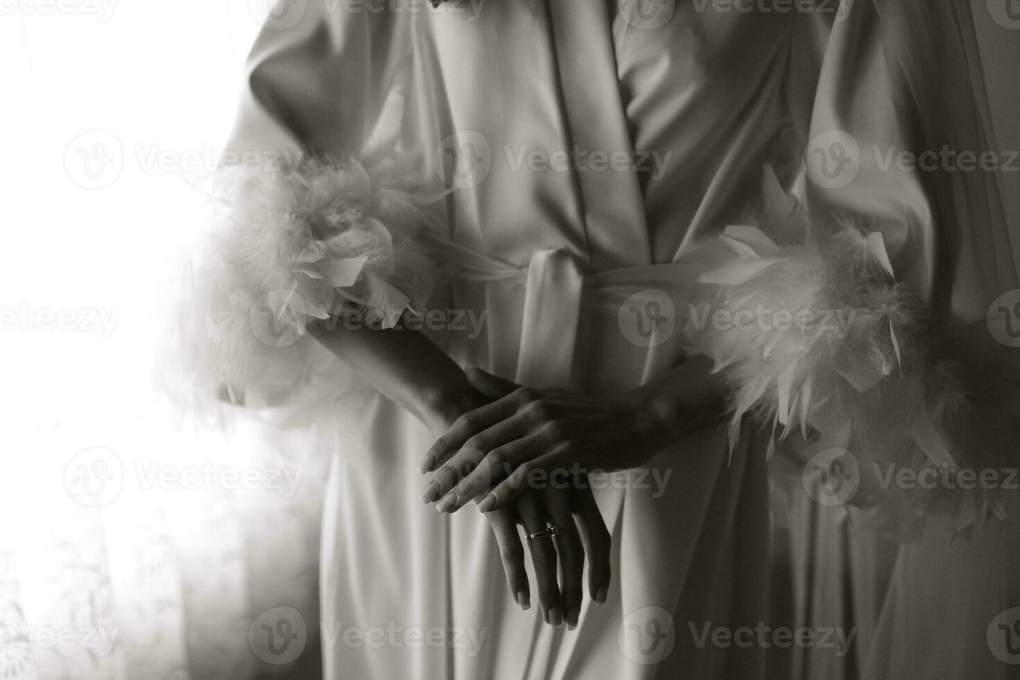 Morning of the bride, woman wearing a white silk robe, close-up photo of female hands. Black and white photo