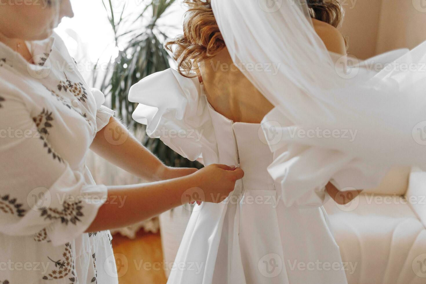 contento novia y dama de honor son preparando para el boda, Ayudar en el habitación. apoyo, amor y joven mujer en Mañana ropa con amigo o hermana foto