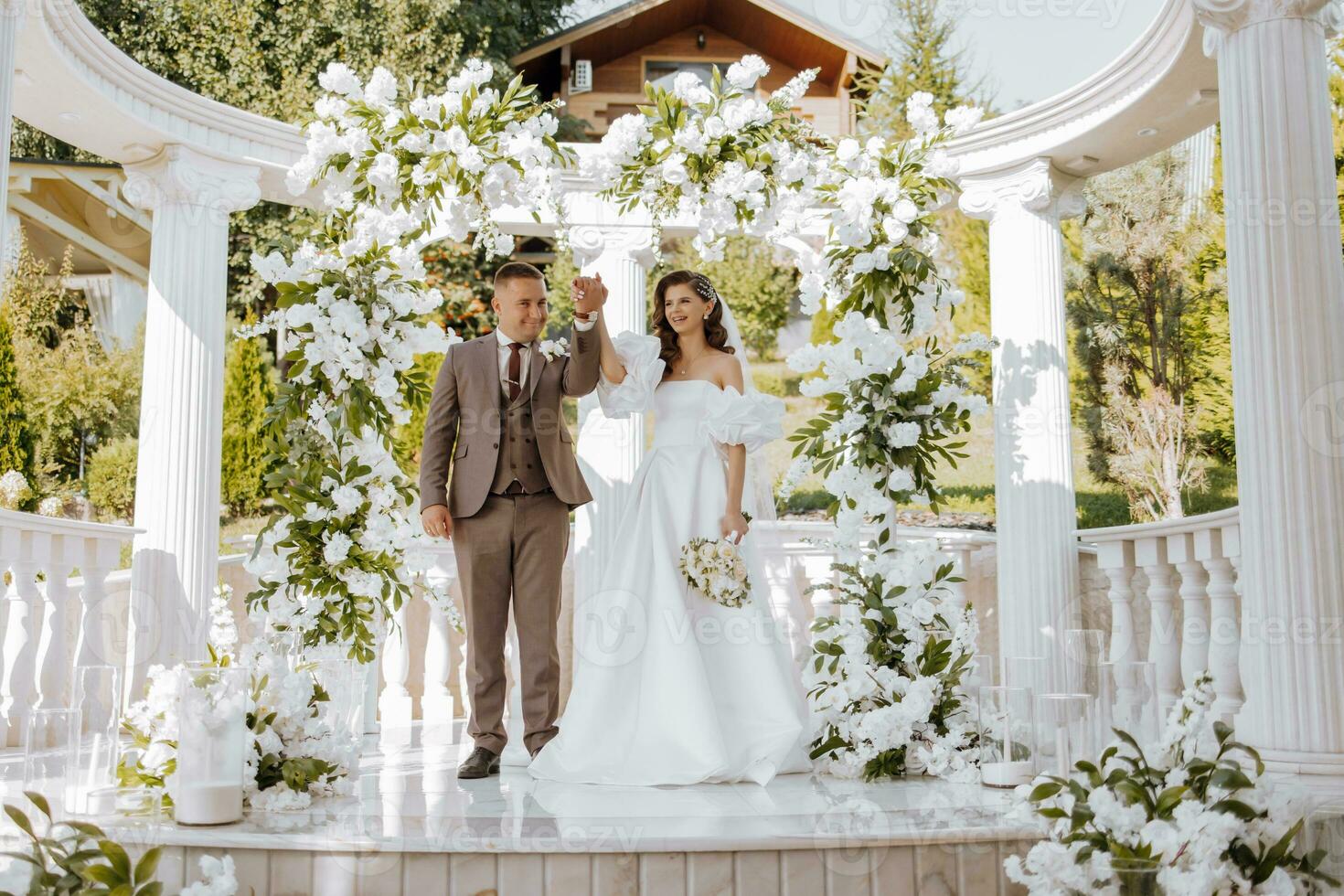 sensible ceremonia de el novia y novio. un contento recién casado Pareja soportes en contra el antecedentes de un Boda arco decorado con Fresco flores foto