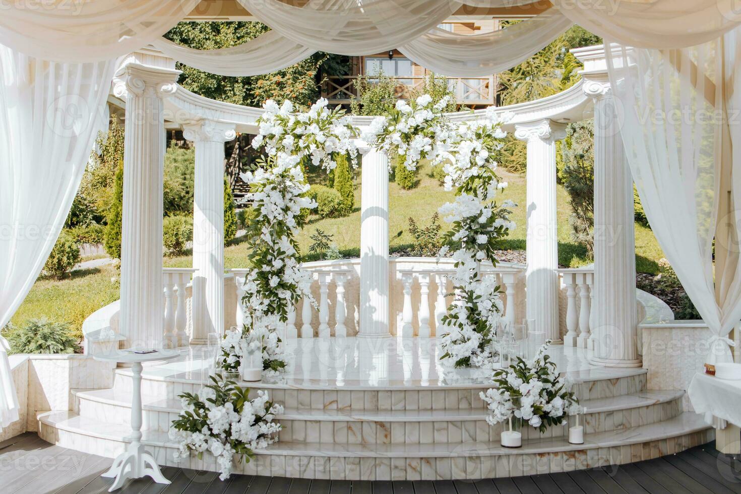 el Boda ceremonia es decorado con Fresco flores en el ubicación con alto blanco columnas preparación para el Boda ceremonia foto