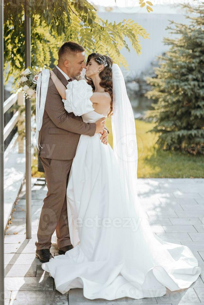 Beautiful bride in a chic wedding dress embraces the groom outdoors in the sunset light, wedding, marriage, relationship, lifestyle photo