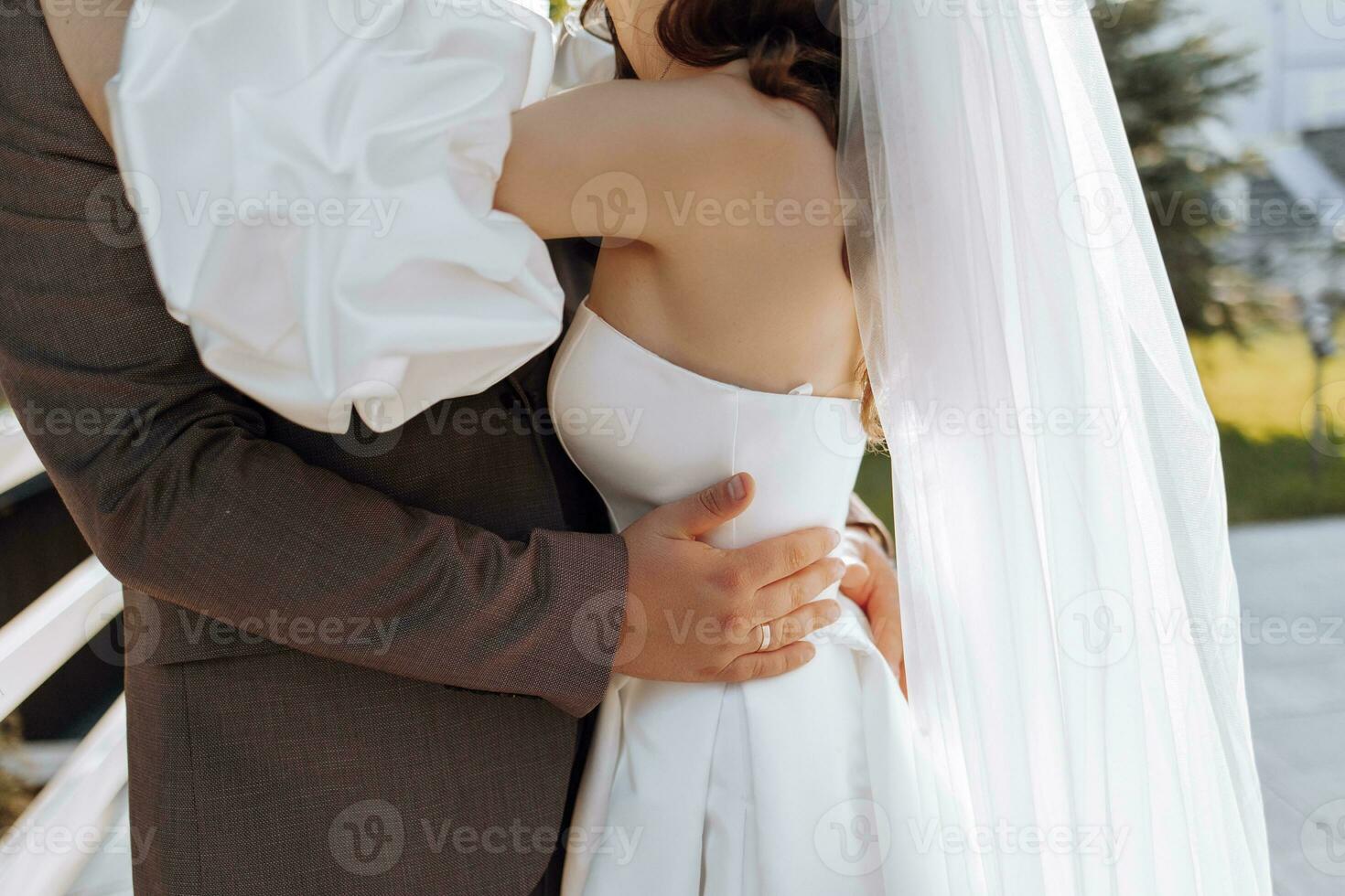 Close up of groom's hands embracing bride from behind outdoors in sunset light, wedding, marriage, relationship, lifestyle photo