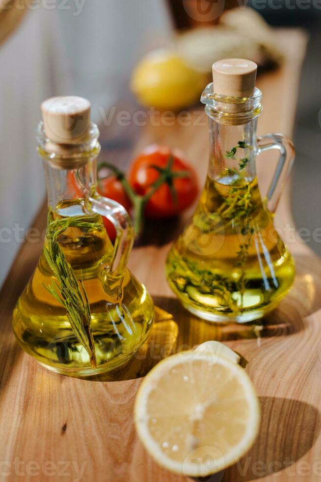 aceituna petróleo en vaso botellas con limón y tomate en de madera mesa foto
