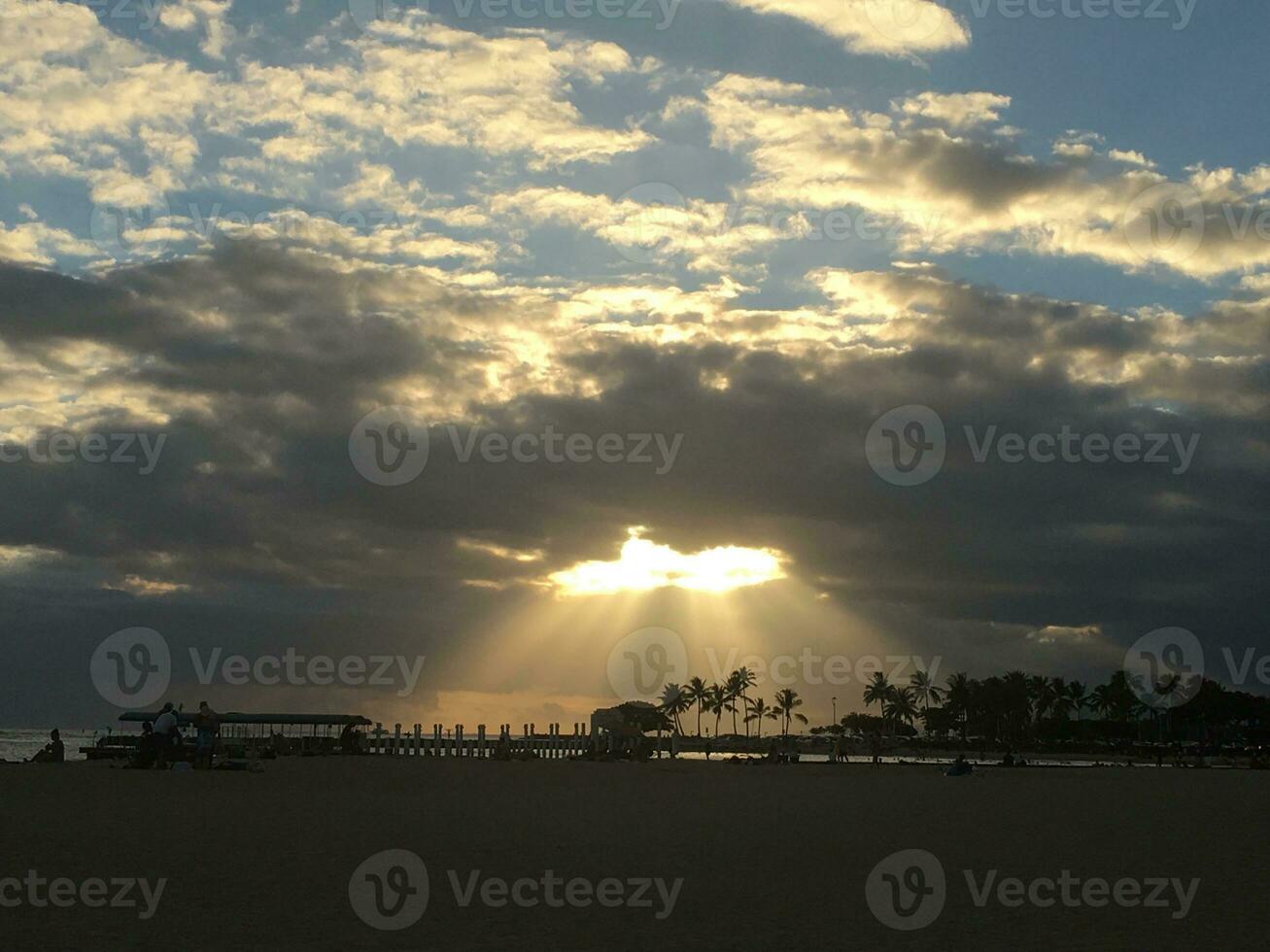 Sunset on the beach with sun rays and palm trees in the background photo