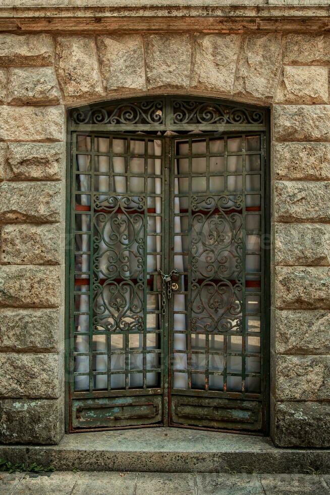 Old door with iron grille in the stone wall of the building photo