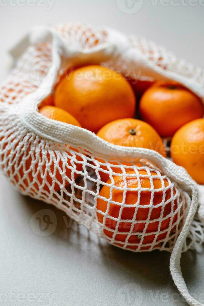 Tangerines in a mesh bag on a gray background. Selective focus. photo