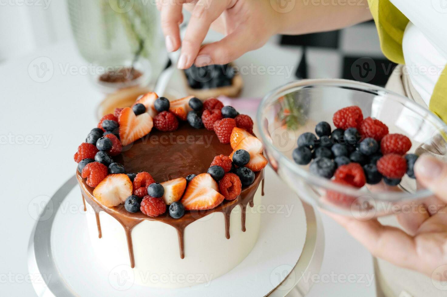 Close-up of female hands decorating chocolate cake with berries. photo