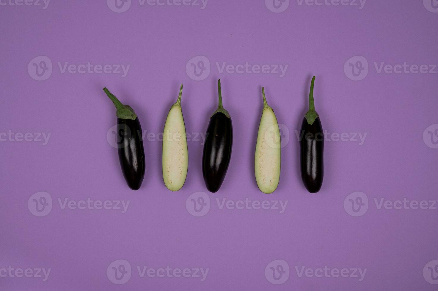Eggplant on purple background. Flat lay, top view. photo