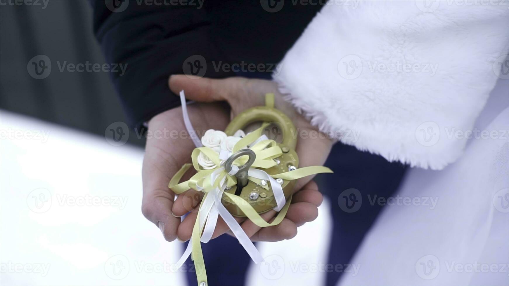 Wedding symbol, lock in hands of bride and groom. Newlyweds fix the lock on the bridge as a symbol of love. Padlock in the hands of the bride and groom. Lock in heart shape on the railing of bridge - photo