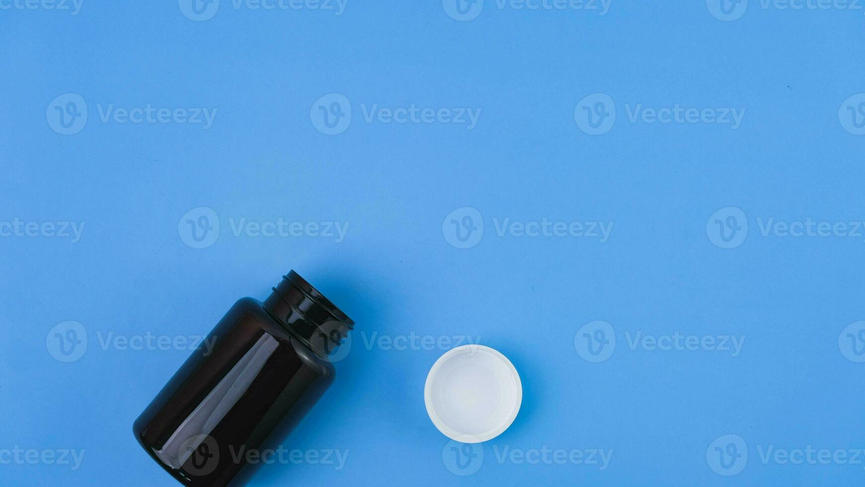 Pill capsule pouring from pharmacy bottle on blue background. Health care concept. photo