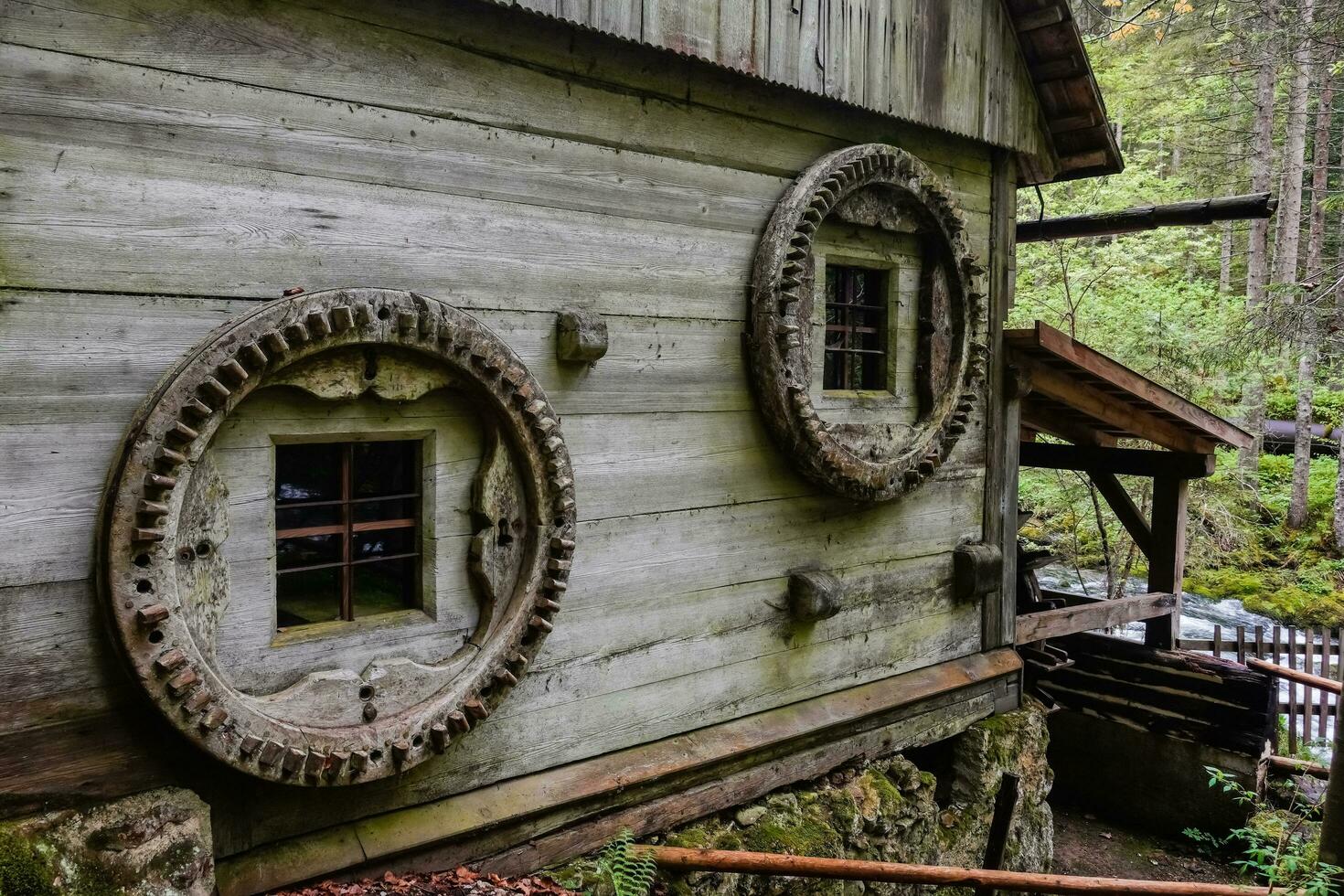 antiguo molino de agua hecho de madera con redondo ventanas en un verde bosque detalle foto