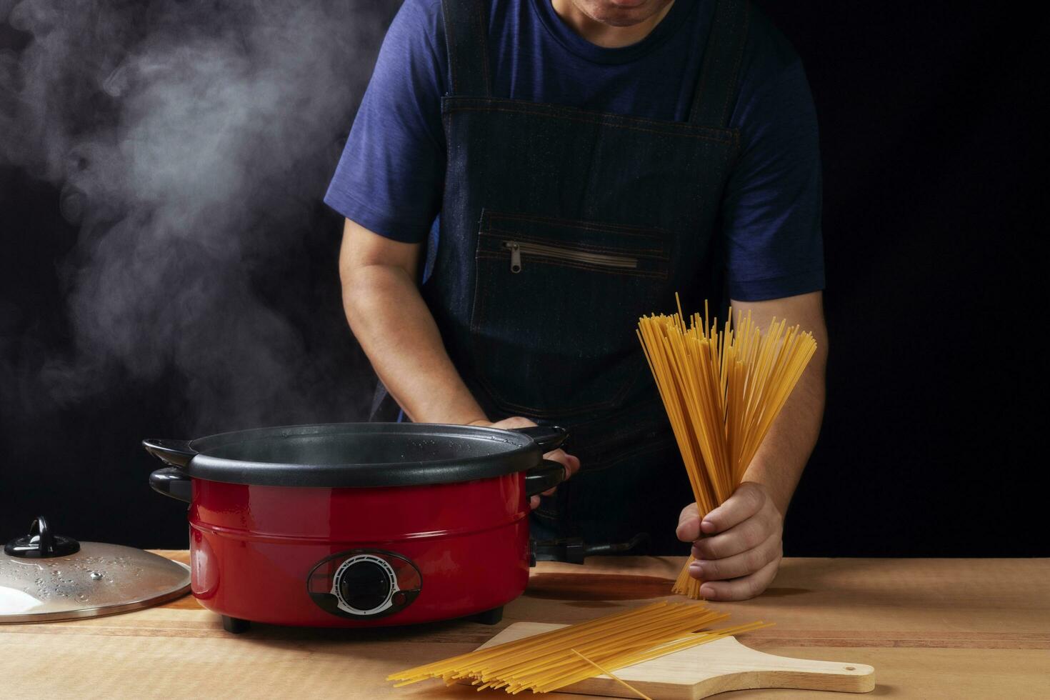 The chef makes spaghetti in a pot In the kitchen, the atmosphere is rustic. Molecular Gastronomy Free space for advertising, black, dark background. photo