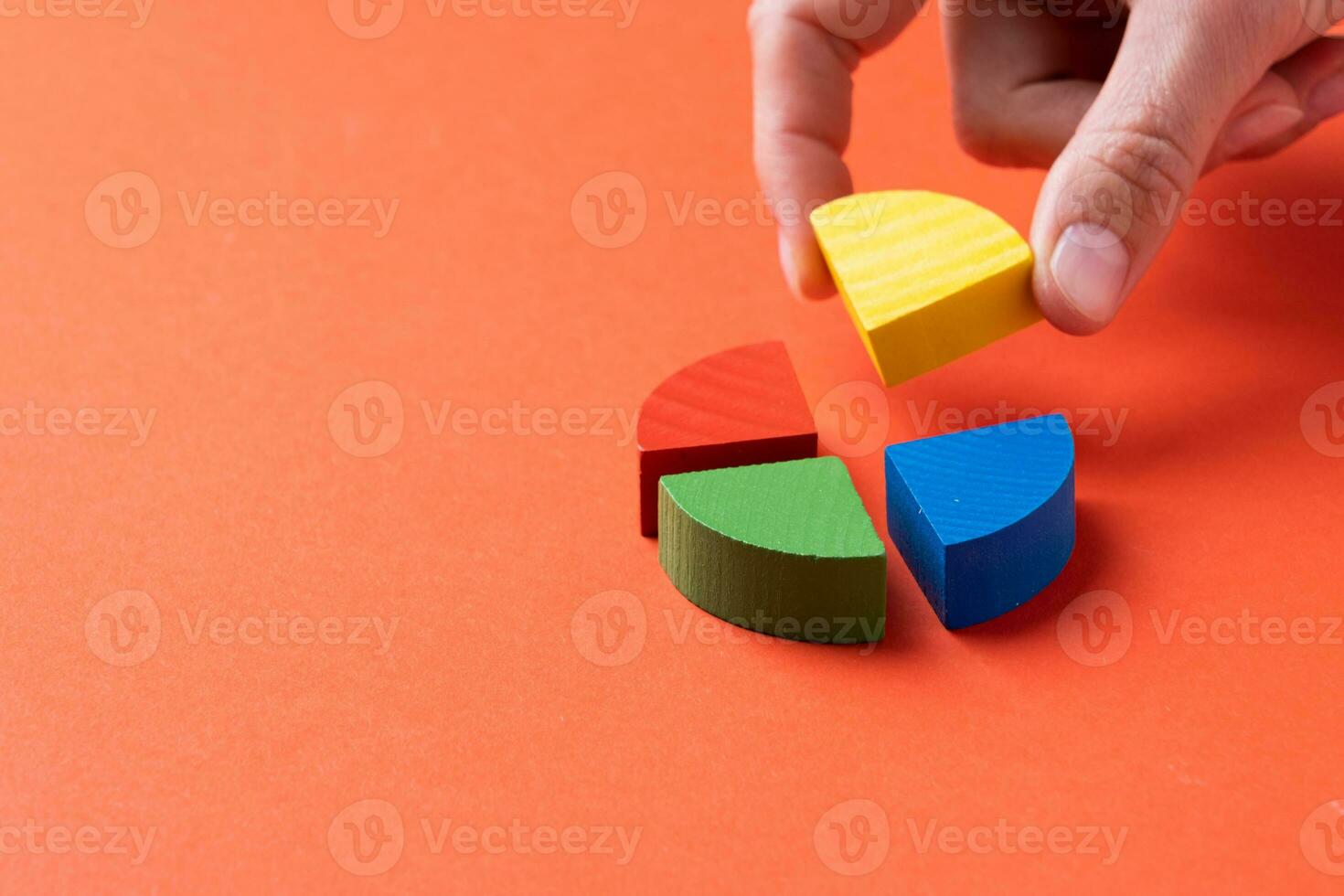 Colorful wooden pie chart pieces, fingers adding piece of diagram photo