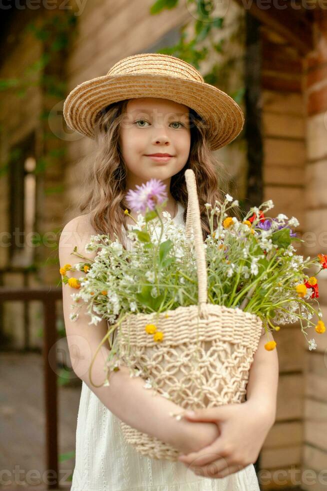 Smiling preteen girl holding wicker basket with colorful wildflowers on summer day photo