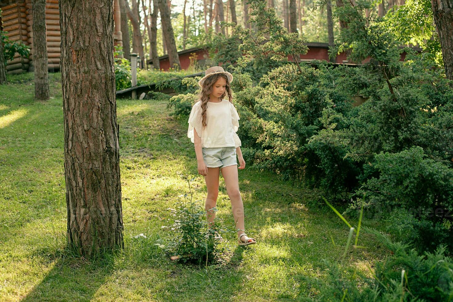 Relaxed tween girl walking in green park of country house on summer day photo