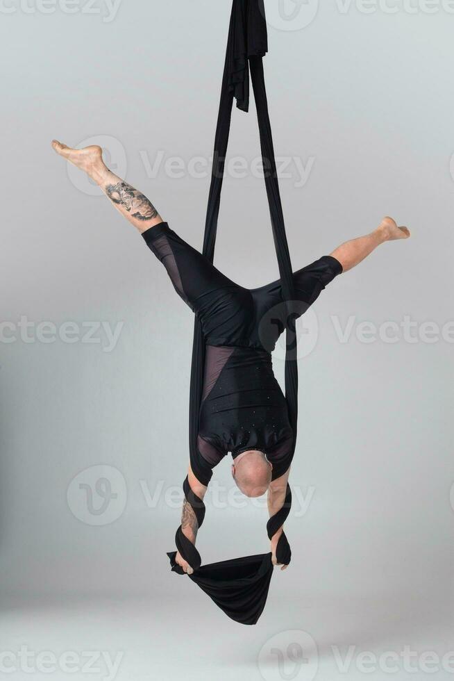 atlético hombre en un negro deporte traje es ejecutando un acrobático elementos en un estudio. foto